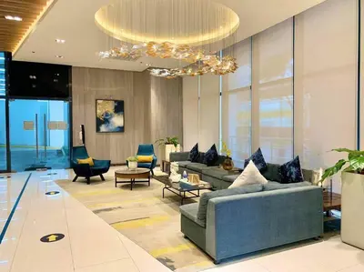 a living room with couches and chairs and a chandelier at 1BR executive unit in Uptown Parksuites BGC in Manila