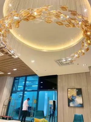 a man standing in a lobby with a chandelier at 1BR executive unit in Uptown Parksuites BGC in Manila