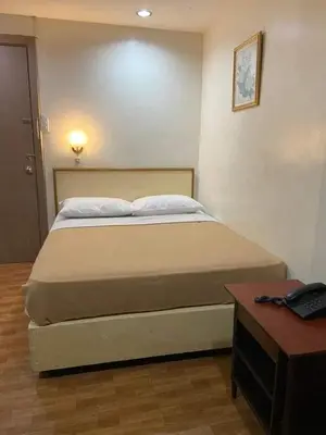 a bedroom with a bed and a table with a telephone at BEST FORTUNE HOTEL at CHINATOWN in Manila