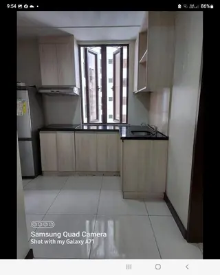 a kitchen with wooden cabinets and a large window at MANILABAY HOME in Manila