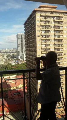 a person taking a picture of a city from a balcony at MANILABAY HOME in Manila
