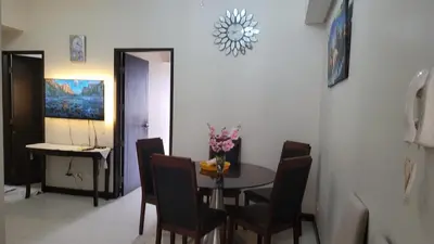 a dining room with a table with chairs and flowers on it at MANILABAY HOME in Manila