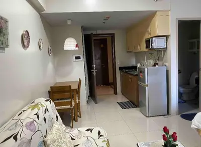 a kitchen with a couch and a table and a refrigerator at S&S CondoTel STUDIO TYPE One Palm Tree Villas in Manila