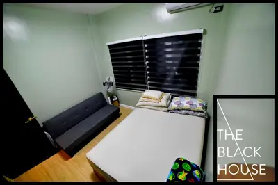 a small room with a black couch and a window at The Black House in Dulong Bayan