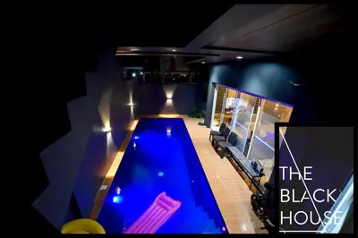 a swimming pool in the middle of a house at night at The Black House in Dulong Bayan