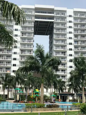 a large apartment building with a palm tree in front of it at MOA CONDOTEL MANILA in Manila