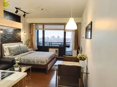a bedroom with a bed and a view of the city at Gramercy Residences studio with Balcony Netflix in Manila
