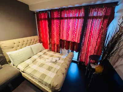a bedroom with a bed and red curtains at Gramercy Residences studio with Balcony Netflix in Manila