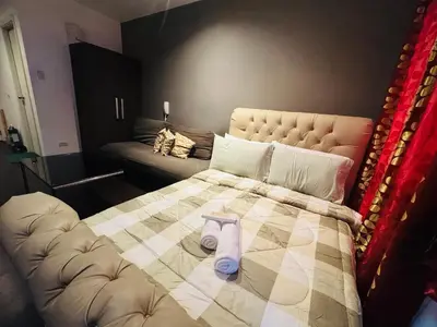 a bedroom with a bed with a blanket and a couch at Gramercy Residences studio with Balcony Netflix in Manila