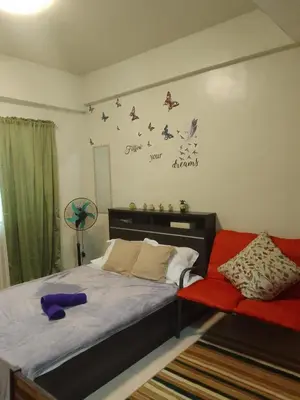 a bedroom with a bed and a red chair at Studio for Rent near Ortigas Extension in Cainta