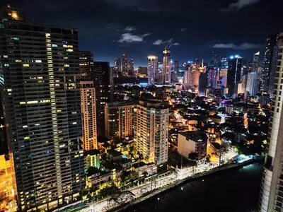 a city skyline at night with a river and buildings at Posada De Michi - Acqua Private Residences in Manila