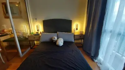 a teddy bear sitting on a bed in a bedroom at Posada De Michi - Acqua Private Residences in Manila