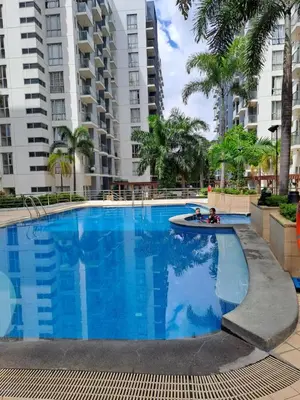 a large swimming pool with two children in it with tall buildings at MRMcondotel in Manila