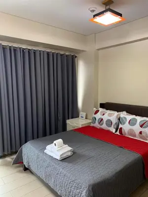 a bedroom with a large bed with black curtains at MRMcondotel in Manila
