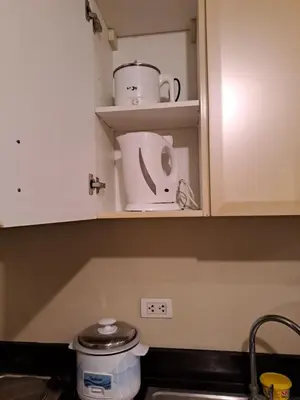 a kitchen counter with white cabinets and a sink at MRMcondotel in Manila