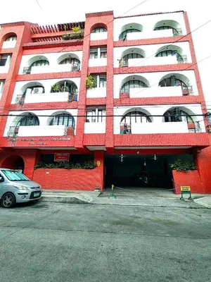 a red and white building with a car parked in front at Rooftop Condo Makati in Manila