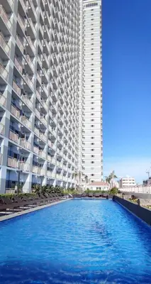 a large building with a swimming pool in front of a building at Jk Coastal Inn in Manila