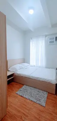 a bedroom with a bed and a window and a rug at SCANDIA SUITES AT SOUTH FORBES Homey & Cozy 2-Bedroom Condo in Silang