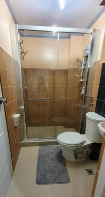a bathroom with a shower with a toilet and a sink at SCANDIA SUITES AT SOUTH FORBES Homey & Cozy 2-Bedroom Condo in Silang