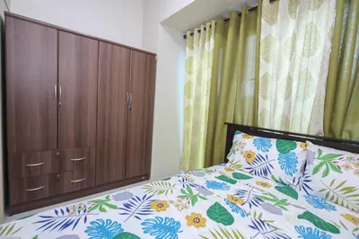 a bedroom with a bed and a wooden cabinet at 1BR Suite @ SM Jazz Residences - WIFI & Netflix in Manila
