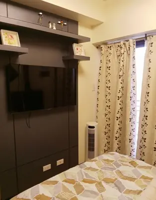 a bedroom with a flat screen tv and a bed at Joey's Place Calathea DMCI in Manila