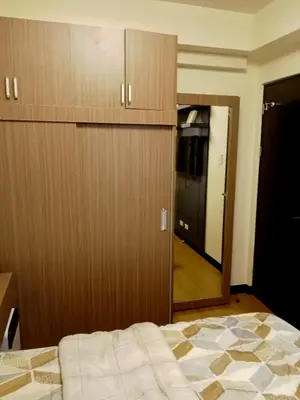 a bedroom with a bed and a closet and a mirror at Joey's Place Calathea DMCI in Manila