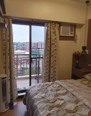 a bedroom with a bed and a large window at Joey's Place Calathea DMCI in Manila