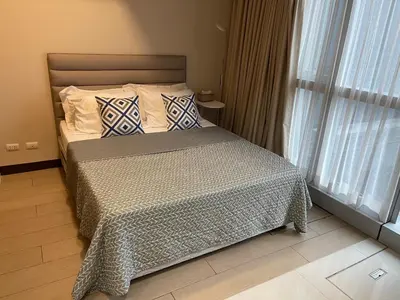a bedroom with a bed with pillows and a window at 1 BR condo Uptown Parksuites BGC, high floor, morning sun in Manila