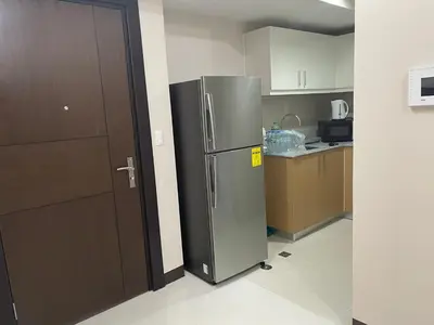 a kitchen with a stainless steel refrigerator next to a door at 1 BR condo Uptown Parksuites BGC, high floor, morning sun in Manila
