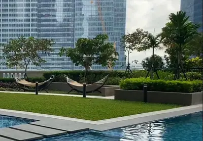a resort with a pool and chairs and buildings at 1 BR condo Uptown Parksuites BGC, high floor, morning sun in Manila
