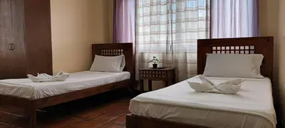 a room with two beds with white pillows at Makabata Guesthouse & Cafe in Manila