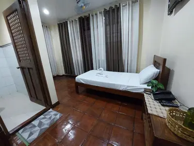 a small room with a bed and a wooden floor at Makabata Guesthouse & Cafe in Manila