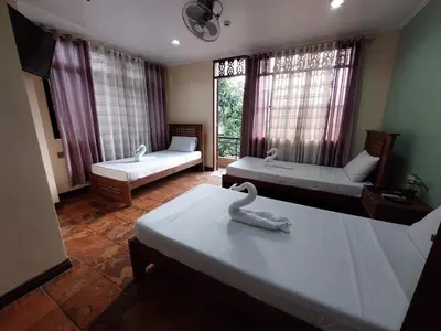 a room with two beds and a large window at Makabata Guesthouse & Cafe in Manila