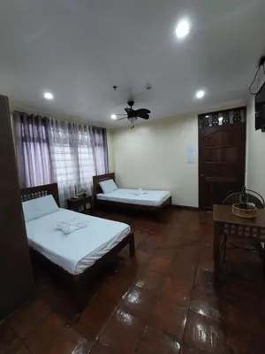 a bedroom with two beds and a ceiling fan at Makabata Guesthouse & Cafe in Manila