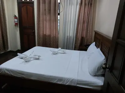 a bedroom with a bed with white sheets and bows at Makabata Guesthouse & Cafe in Manila
