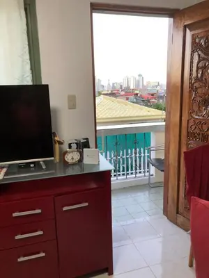 a television on a dresser in a room with a balcony at THE MANSION- Near NAIA Airport Terminal PASAY in Manila