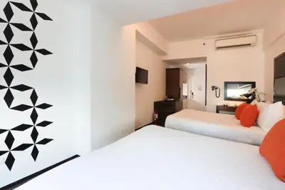 a hotel room with two beds and a tv at Privato Ortigas in Manila
