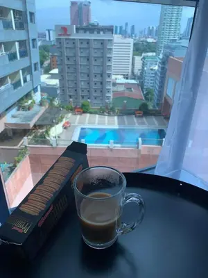 a cup of coffee sitting on a table next to a window at Grand Riviera Suites Comfy Condo near US Embassy Manila Bay Roxas Blvd Ermita Manila in Manila