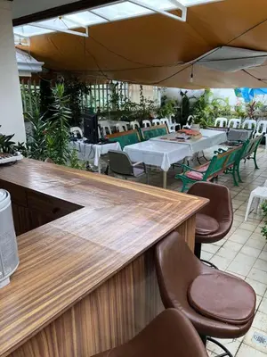 an outdoor restaurant with tables and chairs and an umbrella at THE MANSION - 20 PAX LUXURY Near AIRPORT in PASAY in Manila