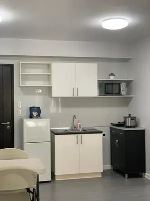 a small kitchen with white cabinets and a sink at Cozy 1 Bedroom near Alabang Town Center and Molito with Wifi and Netflix in Manila