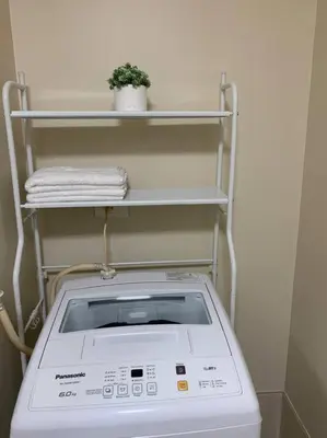 a washing machine in a room with a shelf at Cozy 1 Bedroom near Alabang Town Center and Molito with Wifi and Netflix in Manila
