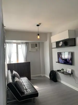 a living room with a leather couch and a tv at Cozy 1 Bedroom near Alabang Town Center and Molito with Wifi and Netflix in Manila