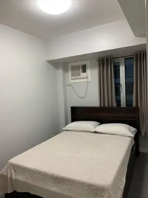 a bedroom with a large bed with a white blanket at Cozy 1 Bedroom near Alabang Town Center and Molito with Wifi and Netflix in Manila