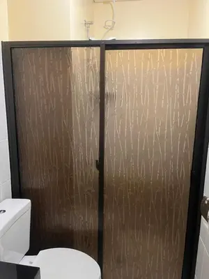 a shower door in a bathroom with a toilet at The Rochester Parklane Condominium in Manila