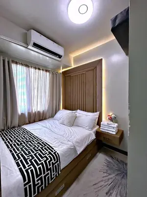 a bedroom with a large bed with a wooden headboard at Cozypura Staycation near MOA, Airport , with free fast WIFI, Netflix and pay parking in Manila