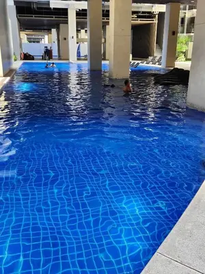 a swimming pool with blue water in a building at Cozypura Staycation near MOA, Airport , with free fast WIFI, Netflix and pay parking in Manila