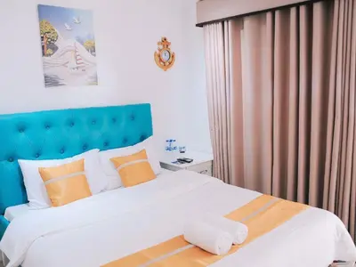 a bedroom with a large bed with a blue headboard at Villa Excellance Beach and Wave Pool Resort in Postema