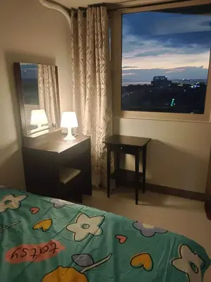 a bedroom with a bed and a desk and a window at Amesha Staycation in Manila