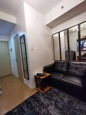 a living room with a black leather couch and a table at Lot's Pad nr BGC in Manila