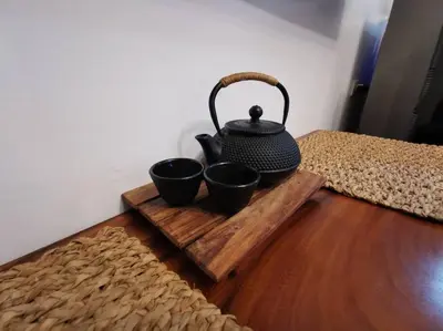 a tea kettle on a wooden tray with three cups at Lot's Pad nr BGC in Manila